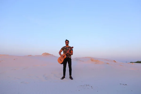 Gutaussehender arabischer Mann, der mitten auf dem Boden stehend Gitarre spielt — Stockfoto