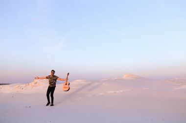 Arap adam çöl güzelliği ile ilham gider ve gitar çi çalış