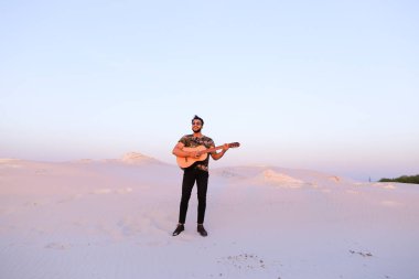 Gitar ayakta bottomle ortasında oynayan yakışıklı erkek Arap