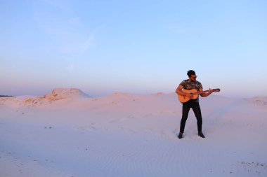 Arap adam çöl güzelliği ile ilham gider ve gitar çi çalış