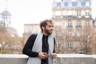 Melez adam akıllı telefon ve kulaklık Eyfel Kulesi ile zevk