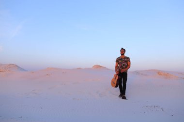 Dese aracılığıyla elinde gitar ile görkemli Müslüman genç adam yürüyor