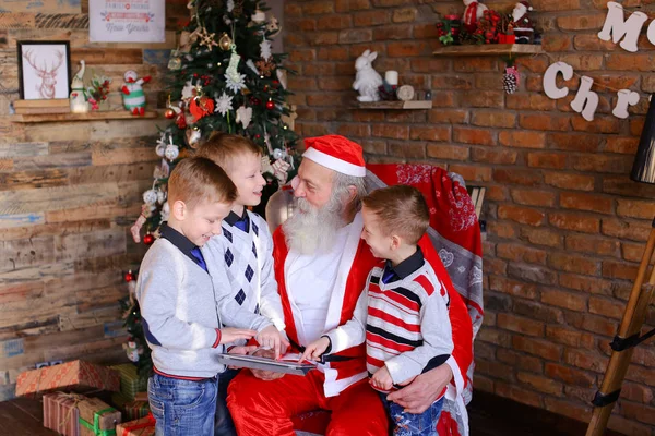 Los chicos enérgicos juegan en la tableta junto con Santa Claus en roo festivo — Foto de Stock