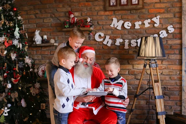 Freundliche Brüder bitten Weihnachtsmann, Karikaturen auf Tablet einzubinden — Stockfoto