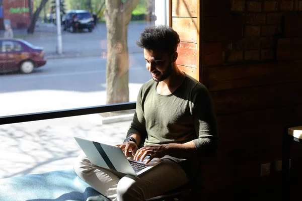 L'uomo si siede nel nuovo appartamento e utilizza il computer portatile . — Foto Stock