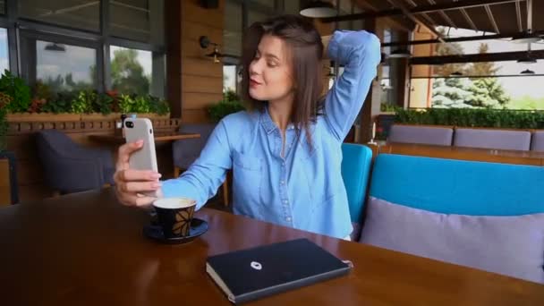 スローモーションでのコーヒーのカップを持つスマート フォンで selfie を作る魅力的な女の子. — ストック動画