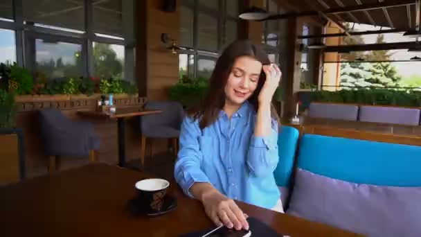 Молодая девушка наслаждается ветреной погодой и играет с волосами в кафе в замедленной съемке . — стоковое видео
