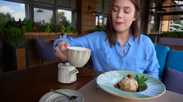 Europejska dziewczyna, picie herbaty w restauracji i będzie jeść tort w zwolnionym tempie. — Wideo stockowe