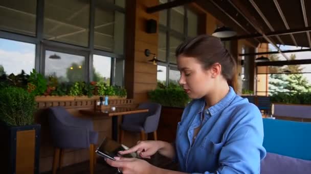 Charmig tjej beter vid tablett på restaurang. — Stockvideo