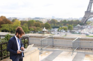 S arka planda Eyfel Kulesi ile dizüstü bilgisayar kullanarak seyahat Yöneticisi