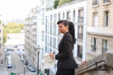 Yarım Nijeryalı muhabir cam balkon gazete ile seyir.