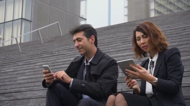 スローモーション男性と女性会社員が階段に座って休憩を過ごす. — ストック動画