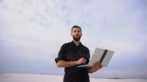 Escritor de cámara lenta masculino con portátil buscar inspiración en la playa . — Vídeos de Stock