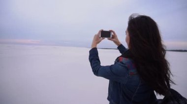 Ağır çekim Gezgin kız fotoğrafları günbatımı yapma smartphone kullanarak.