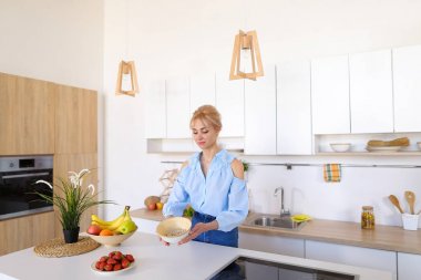 Güzel kadın ev kadını gülümseme ile sağlıklı kahvaltı hazırlar