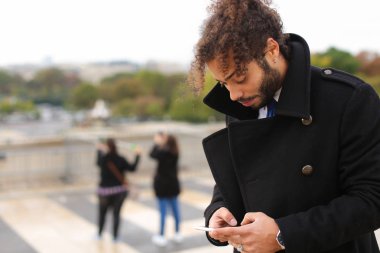 Melez işadamı smartphone cep telefonu ile Eife yakınındaki ortağıyla konuşmak