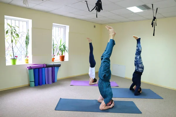 Young woman yoga trainer teaches the boy and girl to do the exer