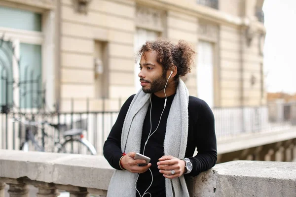 Melez adam akıllı telefon ve kulaklık Eyfel Kulesi ile zevk