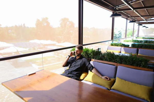 Hombre próspero utilizando el teléfono inteligente para la conversación un banco de energía un — Foto de Stock