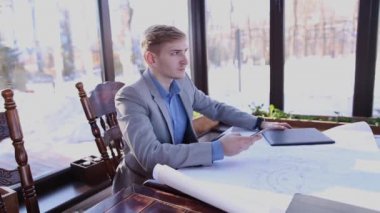 Genç mimar bekleyen istemci proje ve smartphone ile kafeterya masada.