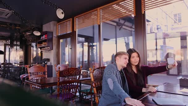 Amigos haciendo selfie en la cámara frontal del teléfono inteligente en la cafetería . — Vídeos de Stock
