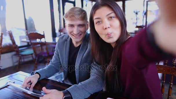 Jocund couple making selfie, using tablet and sticking out tongue. — Stock Video