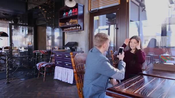 Adam kız fotoğrafı smartphone vasıl Cafe tablo yapma. — Stok video