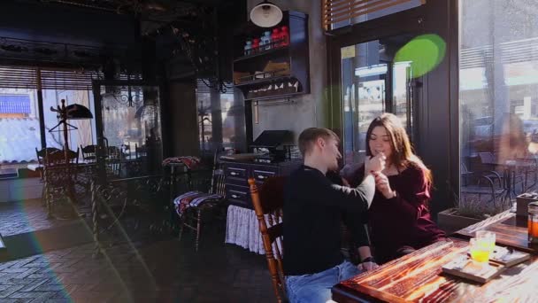 Хлопчик годує гарну дівчину в кафе . — стокове відео