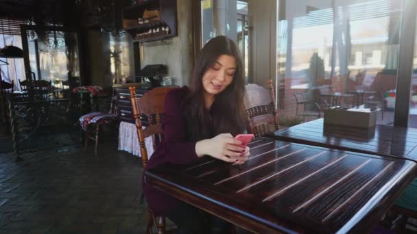 Young woman  Teacher checking tests in cafe using smartphone. — Stock Video