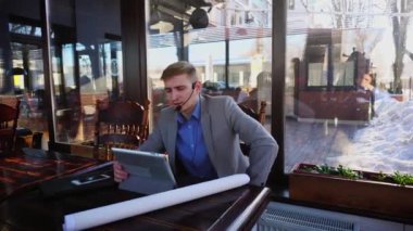 İşadamı Mimar Proje video çağrısı tarafından Café tablet, kulaklık telefon ve mikrofon ile konuşmak hakkında.