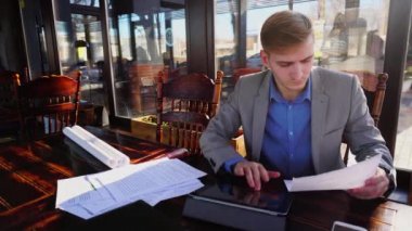 Genç öğrenci sınav kağıtları ve tablet ile kafede hızlı hareket önce hazırlama