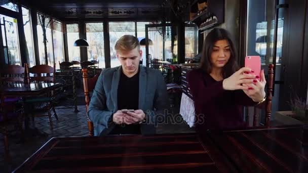 Physicist with smartwatch on hand in cafe with colleague taking selfies using smartphone waiting friend — Stock Video