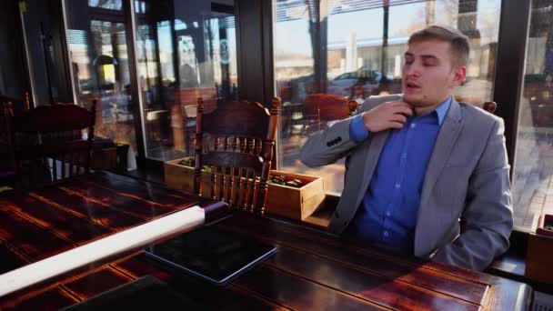 Homem exausto descansando no café e usando tablet perto rolo de papel e documento caso . — Vídeo de Stock