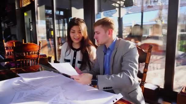 Estudiantes discutiendo sobre arquitectura proyecto de tarea en casa en la mesa de café . — Vídeos de Stock
