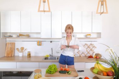 Mutfak kız smartphone elinde tutan ve sebze fotoğrafı çeker