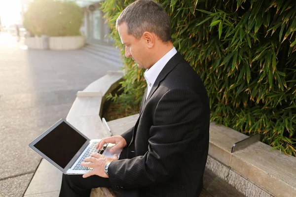 Бизнесмен, работающий с ноутбуком снаружи рядом с заводом в   . — стоковое фото
