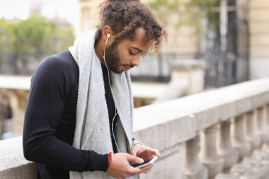 Melez adam akıllı telefon ve kulaklık Eyfel Kulesi ile zevk