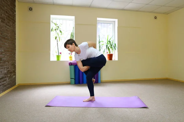 Koyu saçlı güzel genç kadınla yoga egzersizleri gerçekleştirir. — Stok fotoğraf