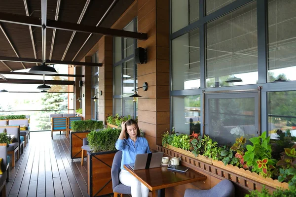 Estudiante charlando por ordenador portátil con amigos en la cafetería . — Foto de Stock