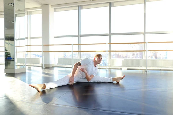 Boy sitting on twine and making stretching.