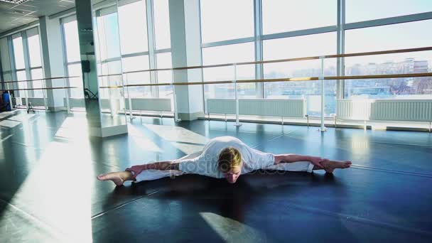 Pojken sitter på garn och göra stretching — Stockvideo