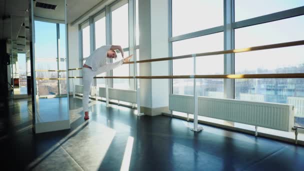 Gimnasta en entrenamiento de ropa deportiva cerca de la barra de ballet en el gimnasio deportivo — Vídeo de stock