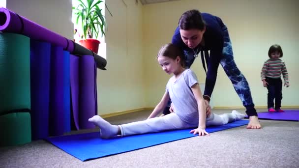 Kleines Mädchen sitzt auf Bindfaden und Trainer hilft Kind. — Stockvideo