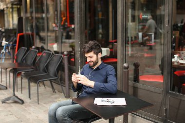 Öğrenci smartphone ve kafede kulaklık ile müzik dinlemek