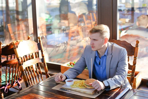 Hombre de negocios vestido con chaqueta gris con reloj inteligente disfrutando de comer — Foto de Stock