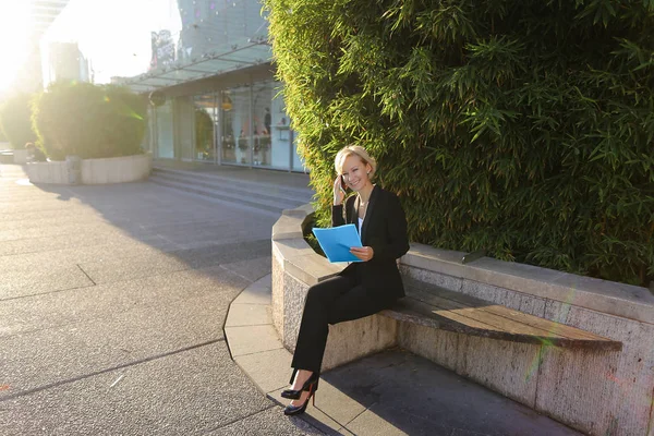 Secretaria hablando por teléfono inteligente con estuche de documentos al aire libre — Foto de Stock