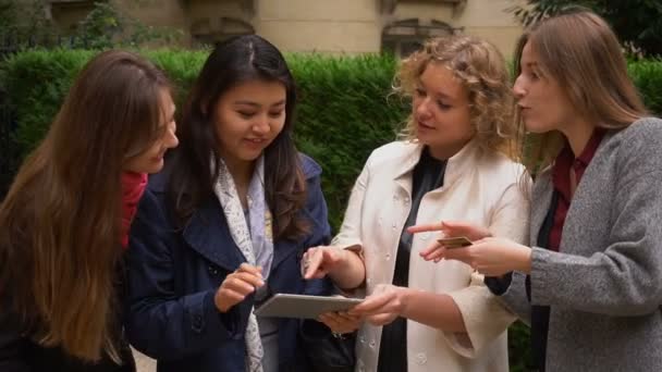 Étudiants internationaux payant avec carte avec tablette au ralenti près du bâtiment universitaire . — Video
