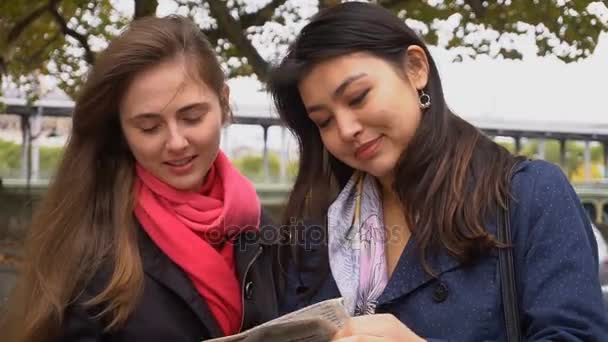 Estudiantes extranjeros buscando piso con periódico afuera . — Vídeos de Stock
