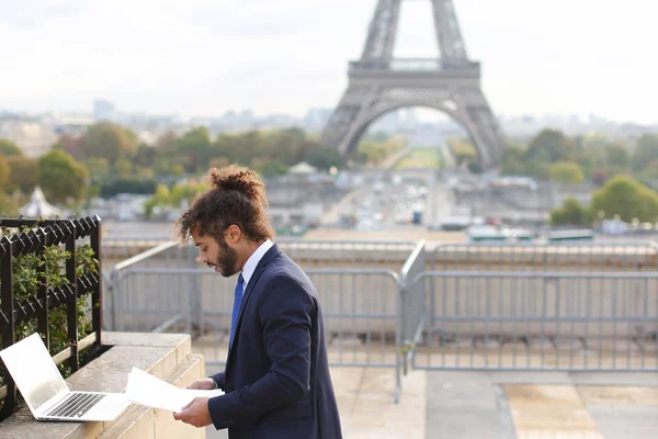 Mixed blood businessman working with laptop near Eiffel Tower in