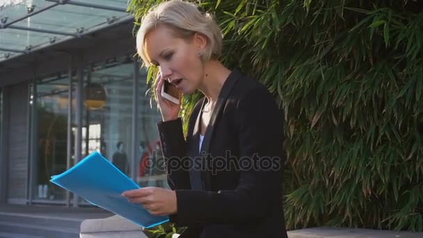 Sekreterare talar av smartphone med dokumentet fall i slow motion utomhus. — Stockvideo